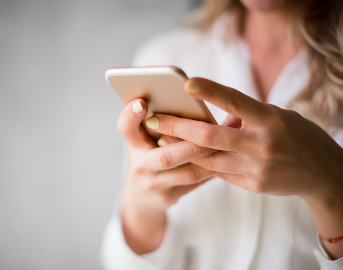 Nahaufnahme einer unscharfen Frau, die ein Mobiltelefon hält und auf die Unify Health-App schaut