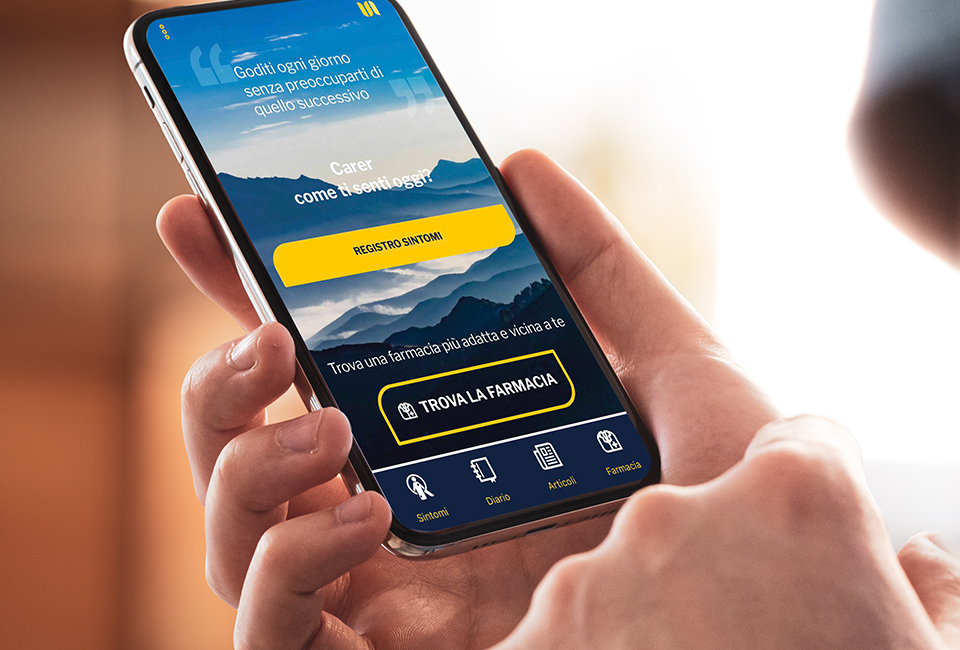 Persona bianca che tiene in mano un telefono cellulare con la dashboard dell'applicazione italiana Unify Health sullo schermo