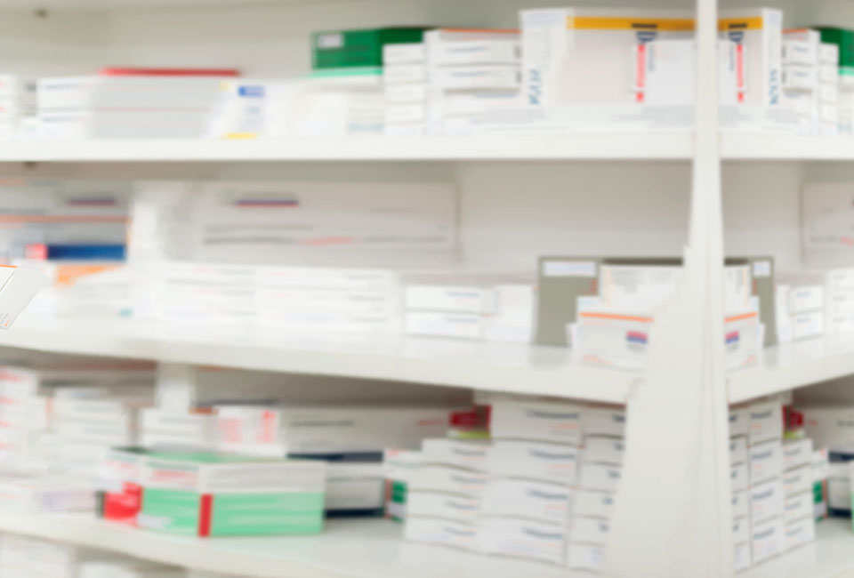 Blurred image of various packets of medication on a Unify Health approved pharmacy shelf